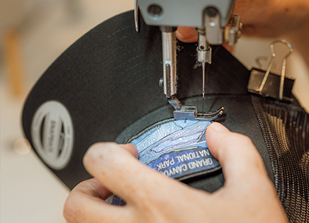 blue label being stitched onto a black hat